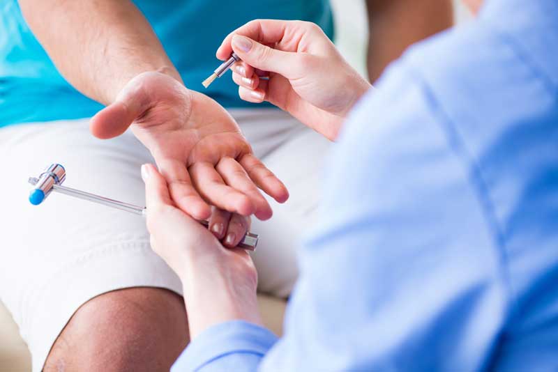 doctor testing patient's wrist reflex with hammer